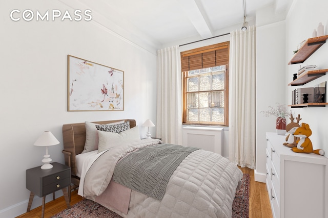 bedroom with light wood-style flooring, beamed ceiling, and baseboards