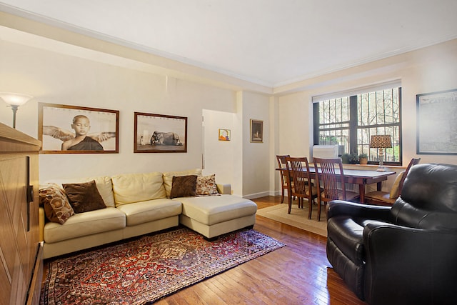 living room with baseboards, wood-type flooring, and ornamental molding