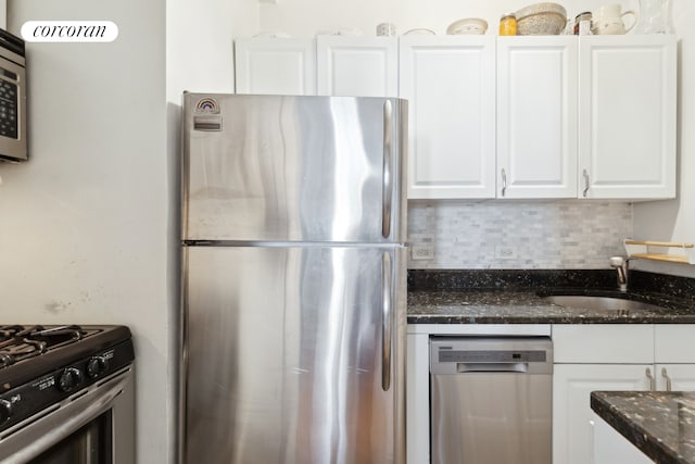 kitchen featuring a sink, dark stone countertops, tasteful backsplash, appliances with stainless steel finishes, and white cabinets