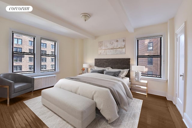 bedroom with beam ceiling, radiator, wood finished floors, and visible vents