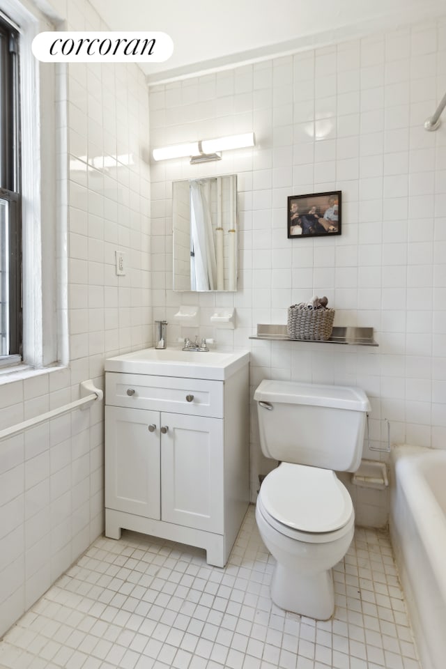 full bath with vanity, a tub, tile walls, toilet, and tile patterned floors