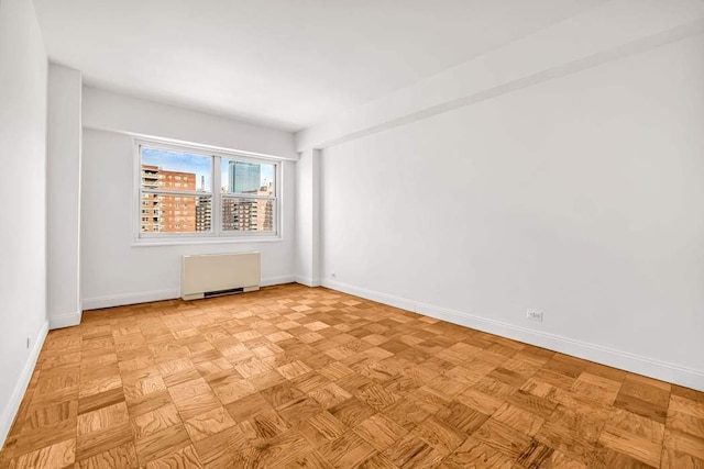 empty room with radiator heating unit and baseboards