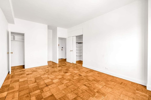 unfurnished bedroom featuring two closets and baseboards