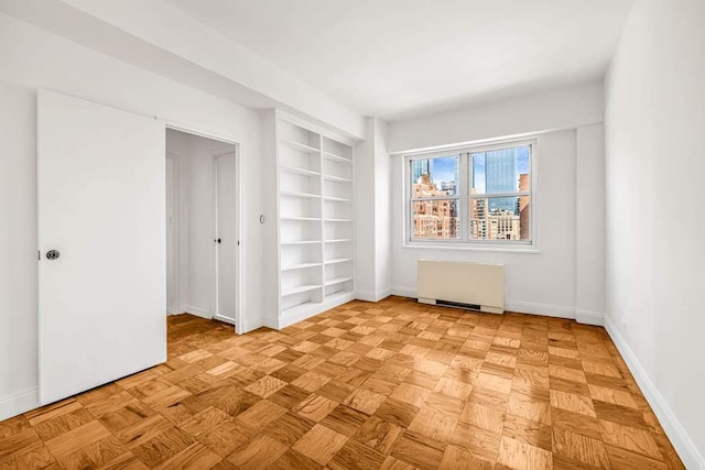 spare room with radiator, baseboards, and built in shelves