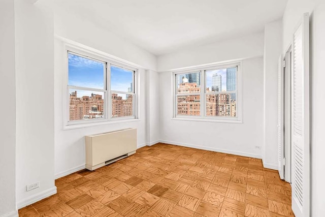 spare room featuring radiator and baseboards