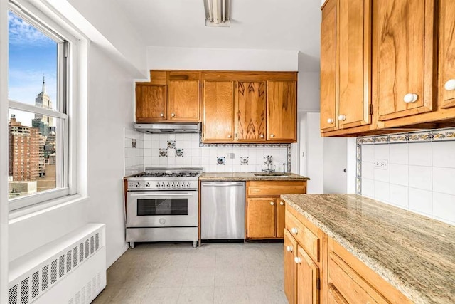 360 W 22nd St Unit 17E, New York City, NY 10011 - kitchen featuring appliances with stainless steel finishes, radiator, brown cabinetry, and backsplash