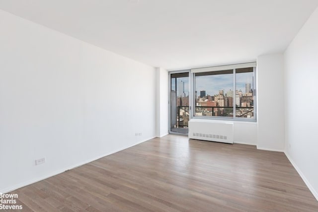 empty room featuring radiator, a city view, and wood finished floors