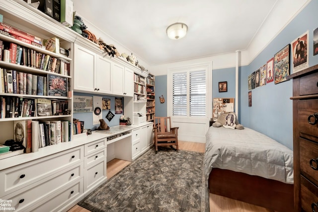 bedroom with built in desk and light wood-style floors