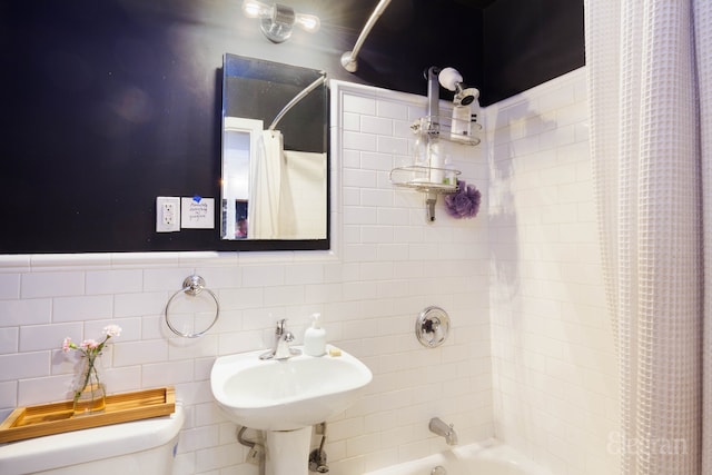 bathroom with shower / bath combination with curtain, toilet, tile walls, and a sink