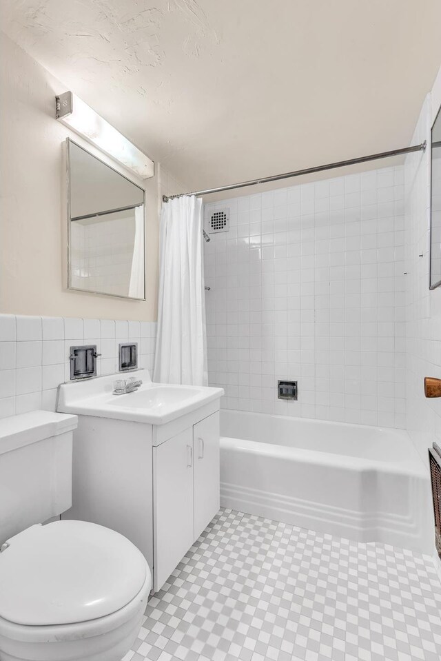 full bathroom with tile walls, toilet, shower / tub combo, tile patterned floors, and vanity