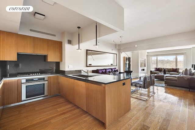 kitchen featuring visible vents, a sink, oven, dark countertops, and open floor plan