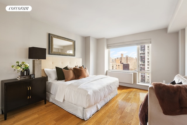 bedroom featuring visible vents, a view of city, and light wood-style flooring