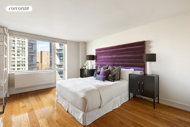 bedroom featuring visible vents, a view of city, baseboards, and hardwood / wood-style floors