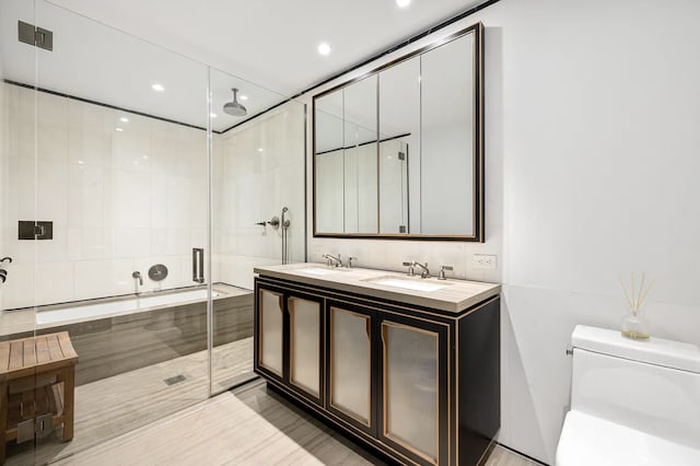 bathroom featuring double vanity, toilet, a stall shower, and a sink