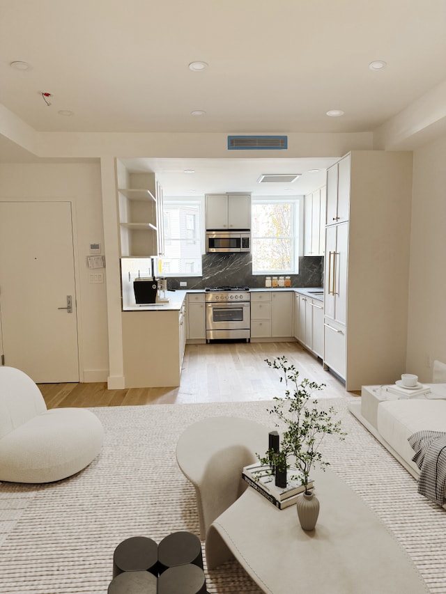 kitchen with tasteful backsplash, stainless steel appliances, light wood-style floors, and open shelves