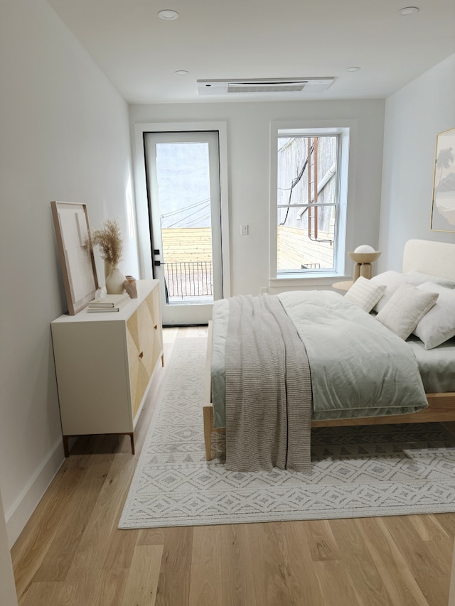 bedroom featuring access to exterior, visible vents, light wood-type flooring, and baseboards