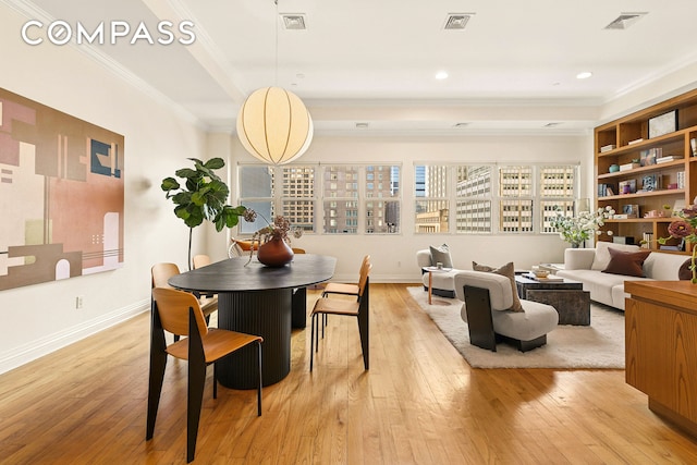 dining space featuring visible vents, crown molding, light wood-type flooring, and baseboards