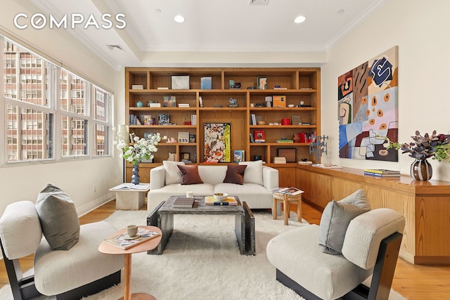 living area featuring crown molding, built in shelves, recessed lighting, and light wood finished floors