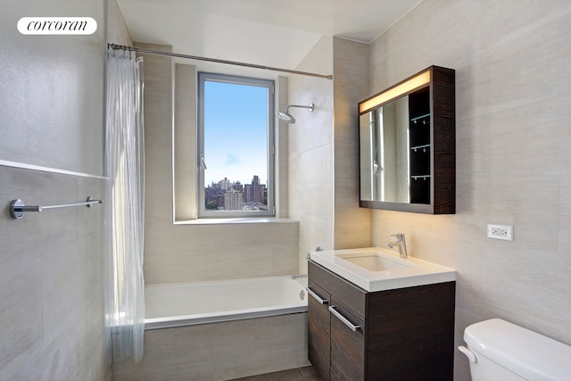 full bath featuring vanity, tile walls, toilet, and tiled shower / bath