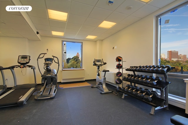 exercise room with a view of city, visible vents, and a drop ceiling