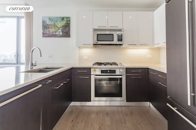 kitchen featuring white cabinets, stainless steel appliances, light countertops, and a sink