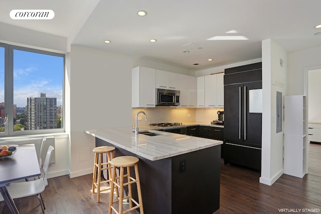 kitchen with stainless steel microwave, visible vents, light stone countertops, a peninsula, and high quality fridge