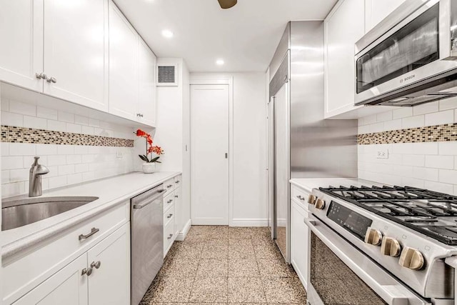 kitchen featuring granite finish floor, a sink, light countertops, appliances with stainless steel finishes, and white cabinetry