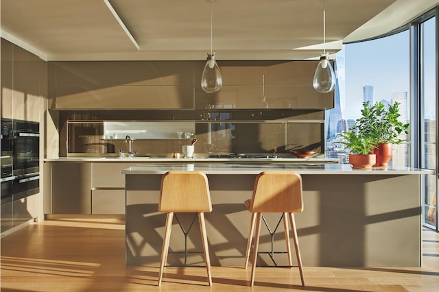 kitchen featuring a breakfast bar area, wood finished floors, oven, a sink, and modern cabinets