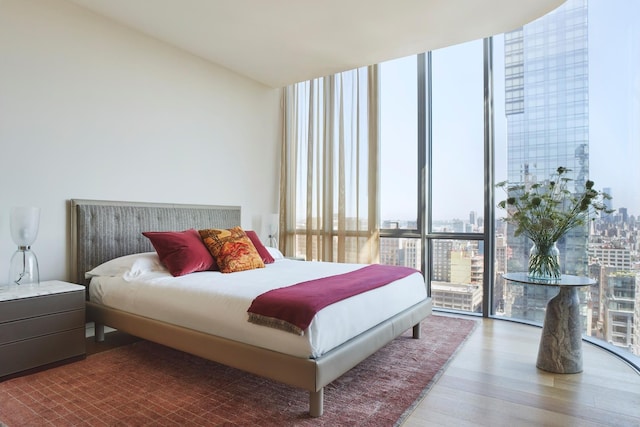 bedroom featuring a city view, wood finished floors, and expansive windows