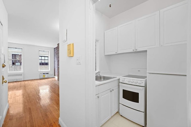 kitchen featuring white appliances, radiator, a sink, light countertops, and white cabinets