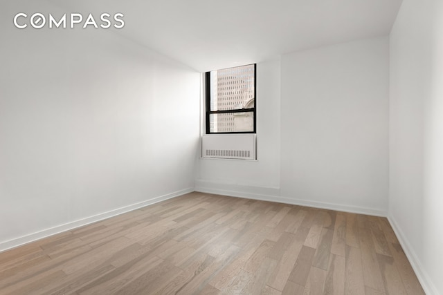 spare room with baseboards and light wood finished floors