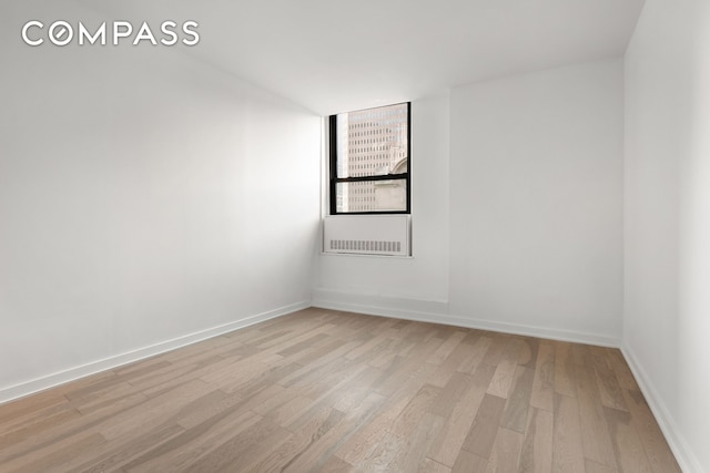 empty room featuring baseboards and light wood-style flooring
