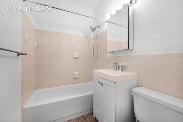 full bathroom featuring vanity, bathtub / shower combination, toilet, and tile walls