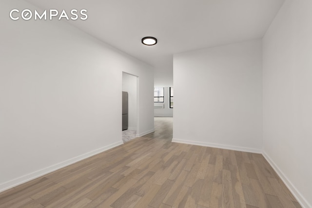 unfurnished room featuring baseboards and light wood-style floors