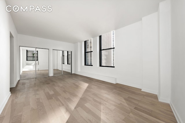 unfurnished bedroom with light wood-style floors, multiple closets, and baseboards