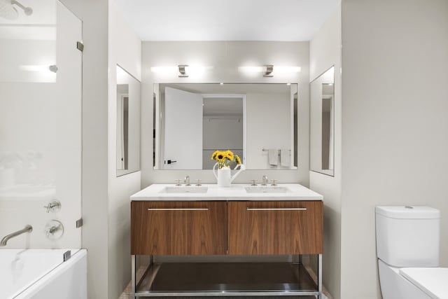 bathroom featuring toilet, a sink, double vanity, and a washtub