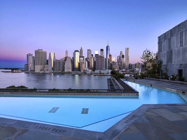 pool at dusk with a water view and a view of city