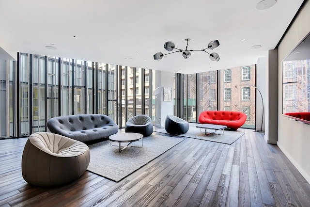living room featuring floor to ceiling windows, a notable chandelier, and wood finished floors