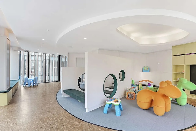 playroom with floor to ceiling windows, a raised ceiling, and recessed lighting