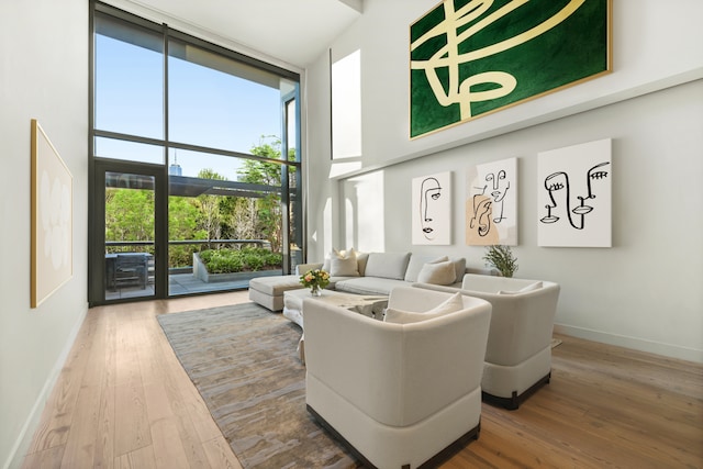 living area with a high ceiling, baseboards, expansive windows, and wood finished floors