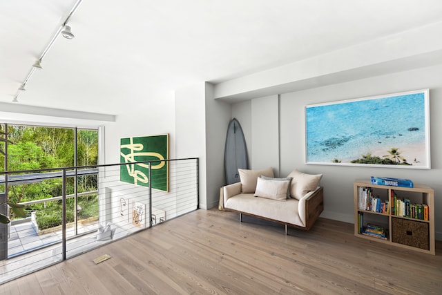 sitting room with track lighting, wood finished floors, visible vents, and baseboards