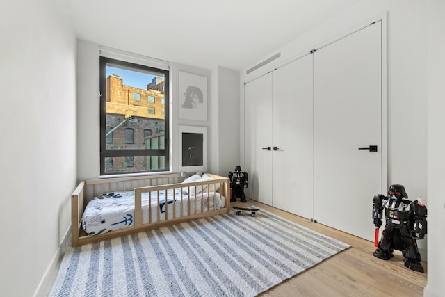 bedroom with a closet, wood finished floors, and multiple windows