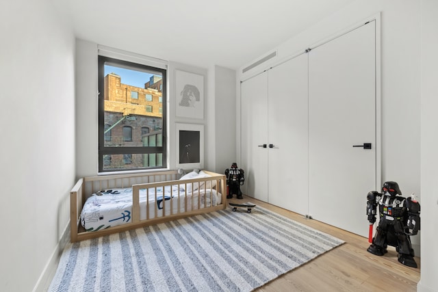 bedroom featuring multiple windows, wood finished floors, and a closet