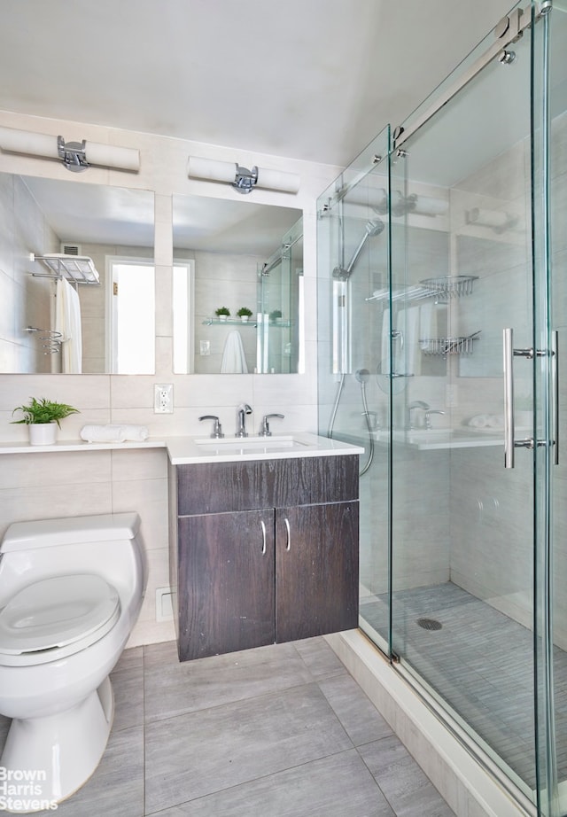 bathroom with tasteful backsplash, toilet, vanity, a stall shower, and tile walls