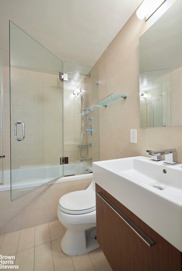 bathroom featuring toilet, tile walls, tile patterned floors, and bath / shower combo with glass door