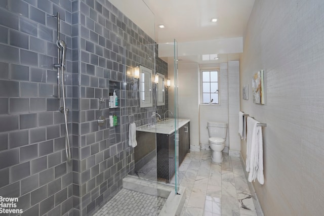 bathroom with tiled shower, toilet, marble finish floor, and vanity