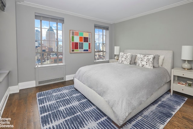 bedroom featuring baseboards, wood finished floors, and crown molding