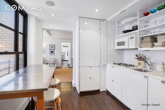 kitchen with white appliances, open shelves, a sink, dark wood-type flooring, and stainless steel countertops