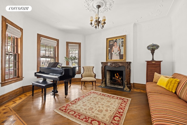 living area featuring visible vents, wood finished floors, a premium fireplace, baseboards, and a chandelier