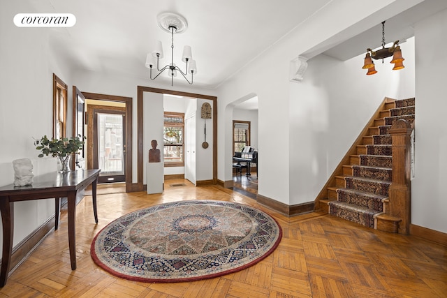 foyer entrance with visible vents, baseboards, a chandelier, stairs, and arched walkways